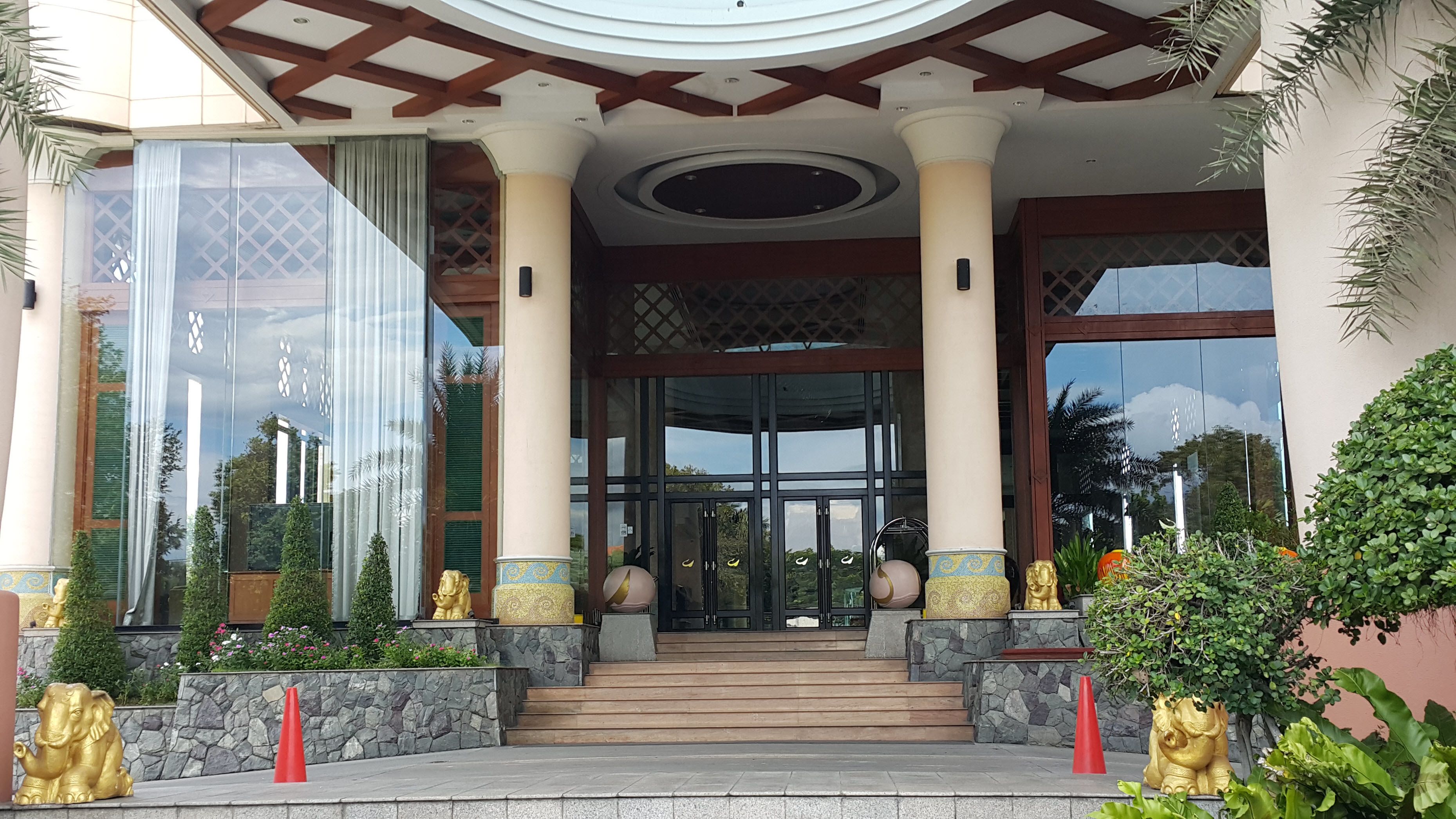 A building entrance with a grand staircase, large glass doors, and decorative golden statues.