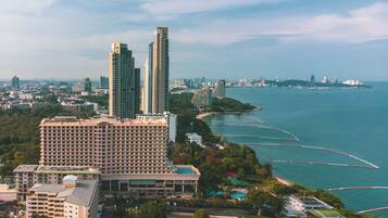 A high-rise hotel with multiple floors, surrounded by lush greenery and a coastal view.