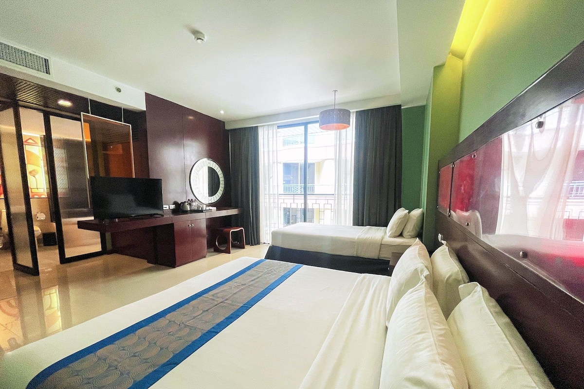 Une chambre d’hôtel avec un lit, un bureau avec une télévision, un miroir et une vue sur l’extérieur.