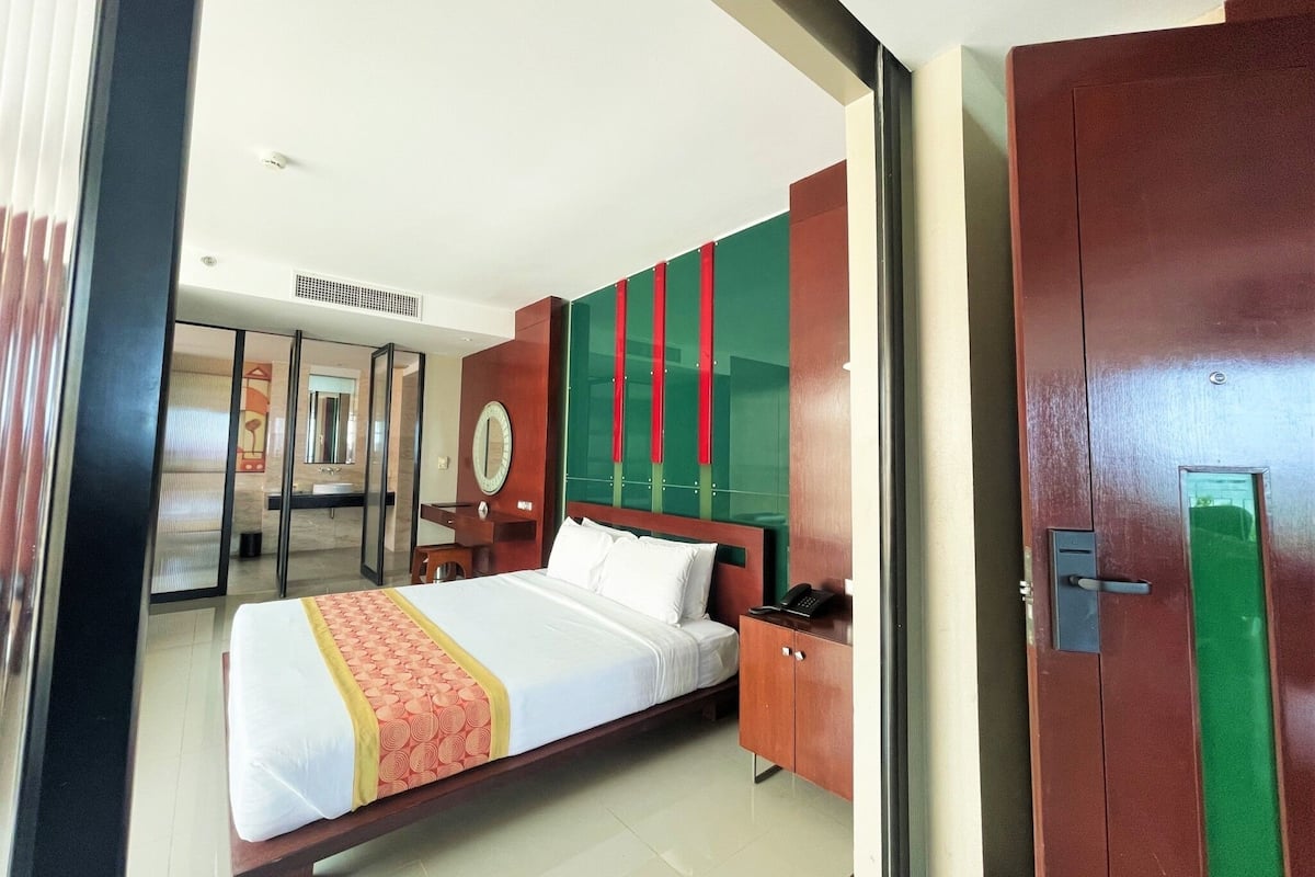 Una habitación de hotel con cama, escritorio, espejo y armario.