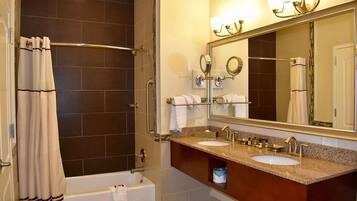 Un baño con ducha a nivel, bañera y tocador con dos lavamanos.