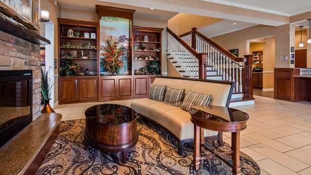 A spacious living room with a fireplace, a sofa, a coffee table, and a staircase leading to another level. - Best Western Plus Easton Inn & Suites (Easton)