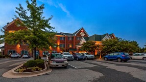 A hotel with a brick facade, multiple parking spaces, and a landscaped area with trees. - Best Western Plus Easton Inn & Suites (Easton)