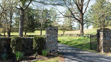 A stone sign with "AIRLIE FARM" and a stone wall with a gate leading to a paved path.