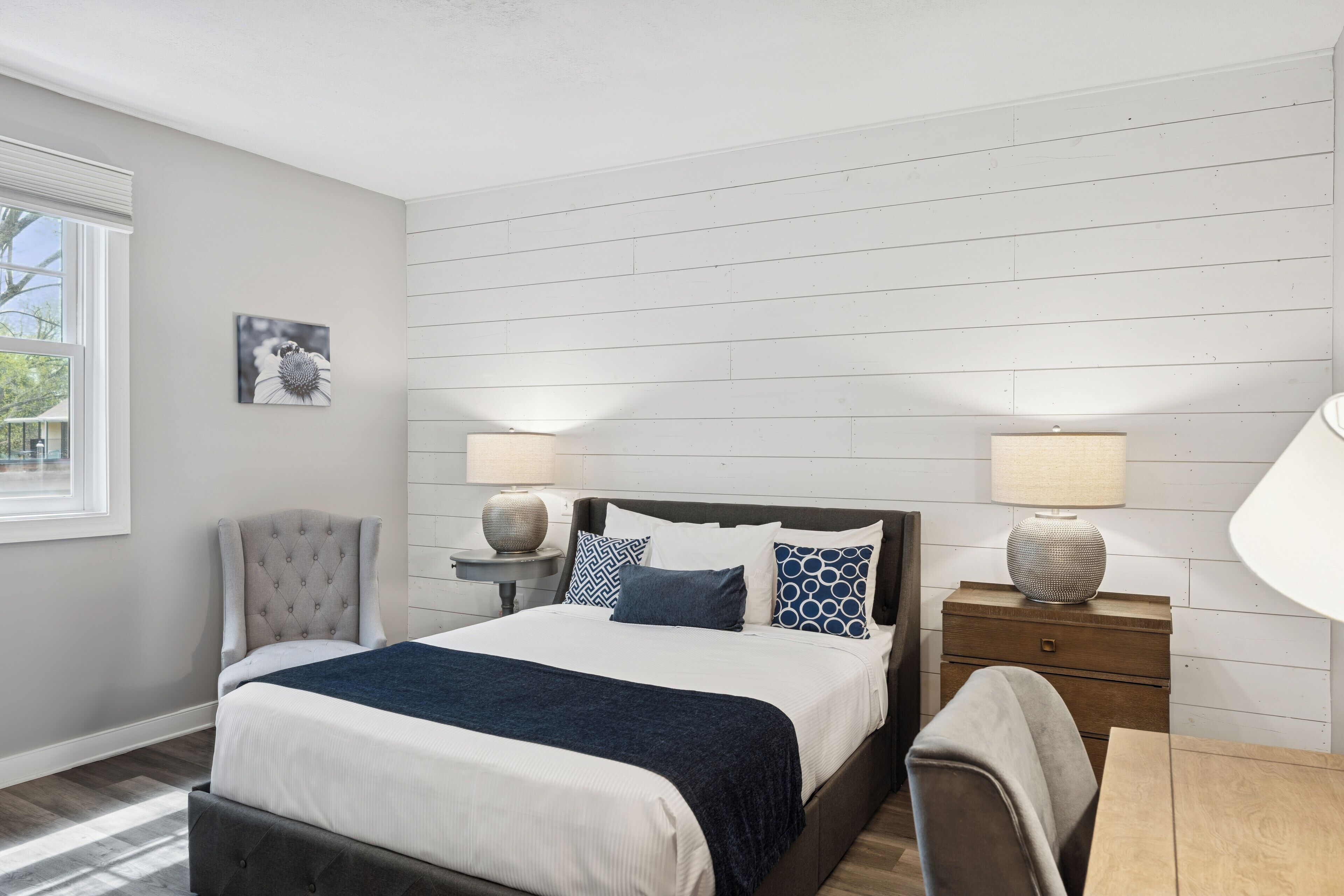 A bedroom with a bed, two bedside tables, a chair, and a lamp.