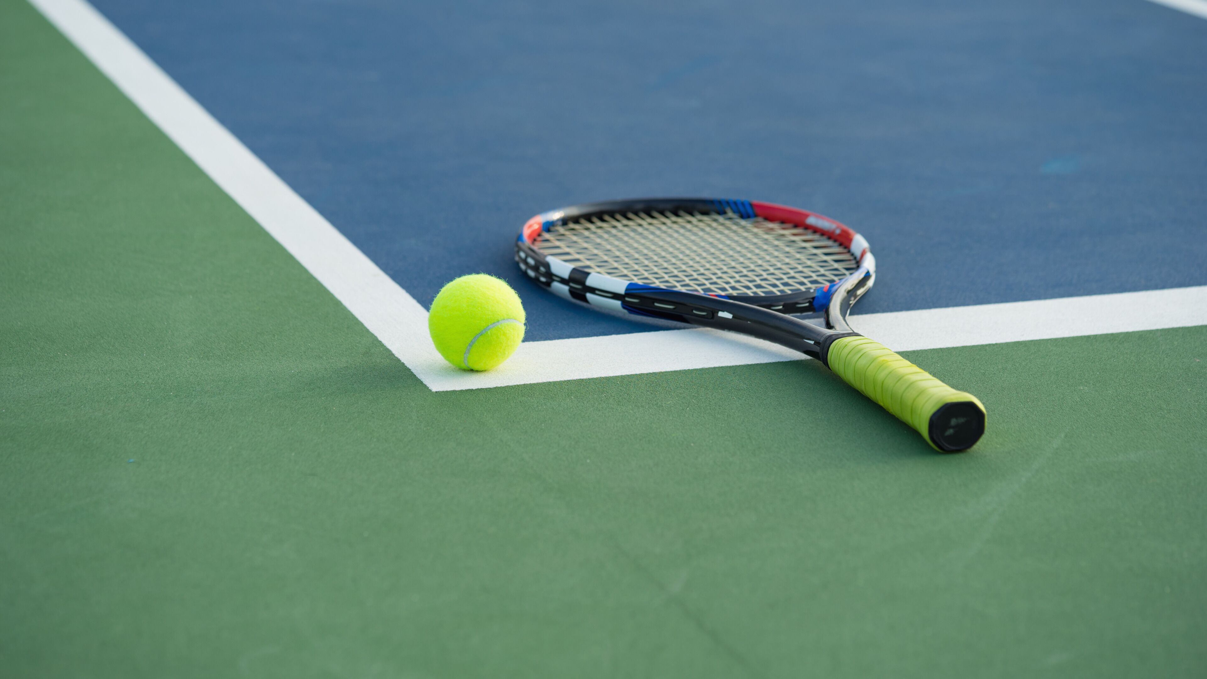 A tennis racket and ball on a tennis court.
