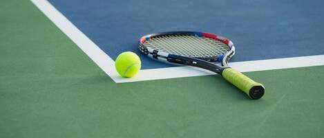 A tennis racket and ball on a tennis court.