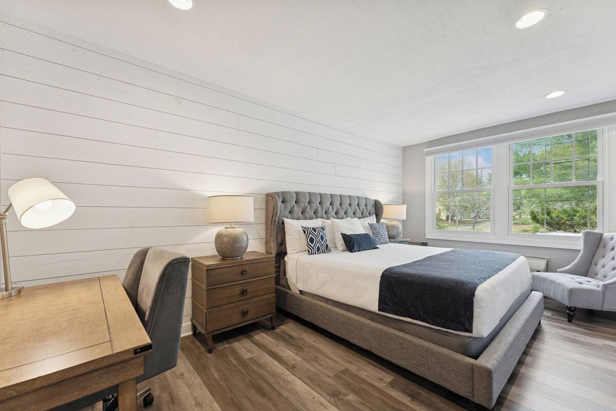 A bedroom with a large bed, a desk, and a chair.