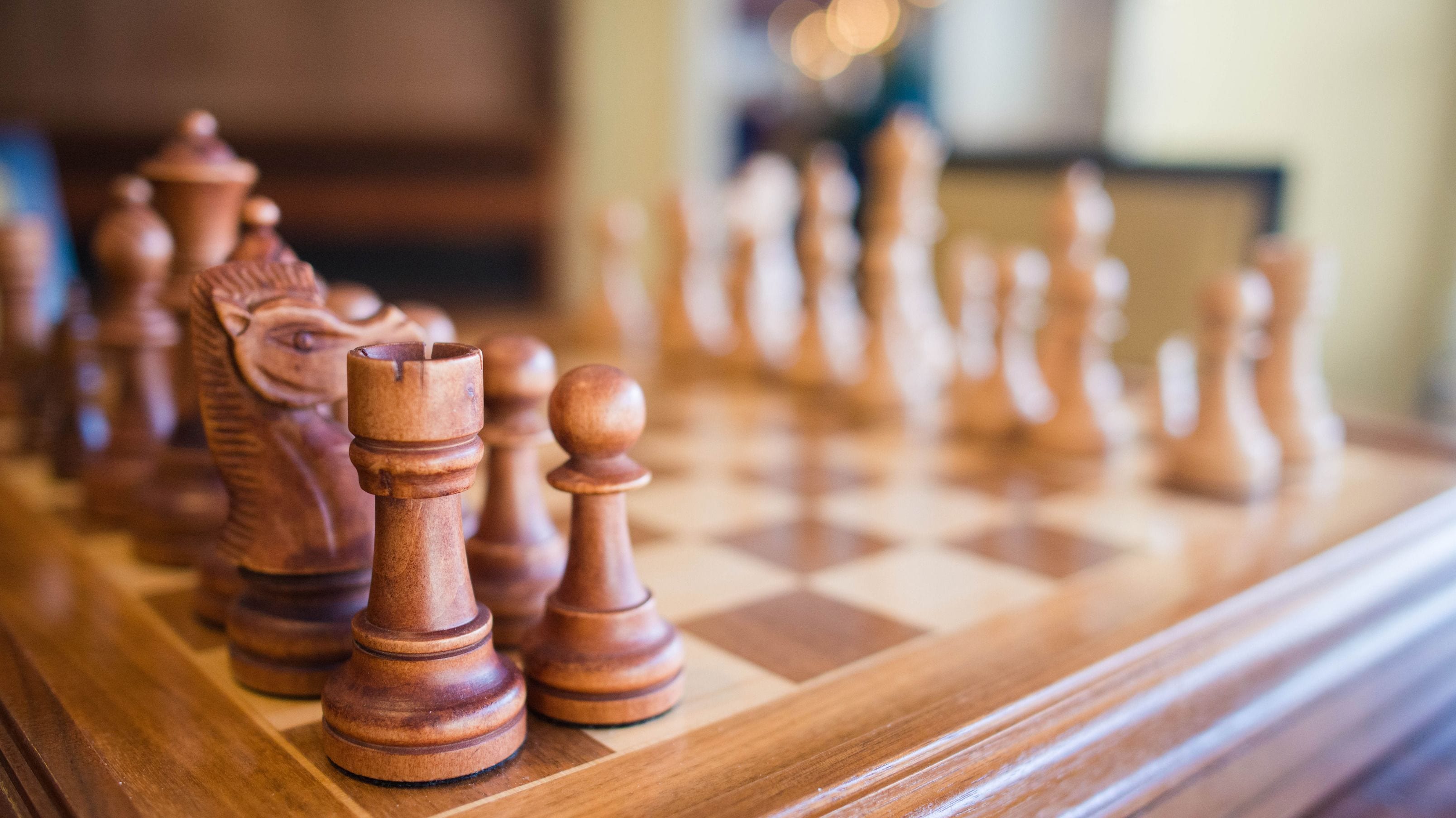 Un tablero de ajedrez de madera, con las piezas en primer plano.