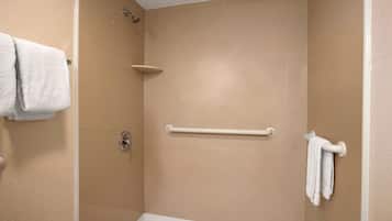 Ein Duschbereich mit beigen Fliesen, einer weißen Haltestange und einem weißen Handtuch an der Wand.