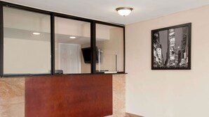A reception area with a marble floor, a reception desk, a large window, and a framed cityscape artwork on the wall. - Super 8 by Wyndham Rahway/Newark (Rahway)