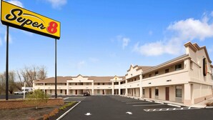 A Super 8 motel with a large parking lot, multiple motel units, and a clear blue sky. - Super 8 by Wyndham Rahway/Newark (Rahway)
