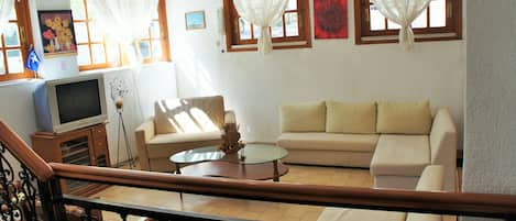 Una sala de estar con un sofá, una mesa de centro y un televisor sobre un mueble.