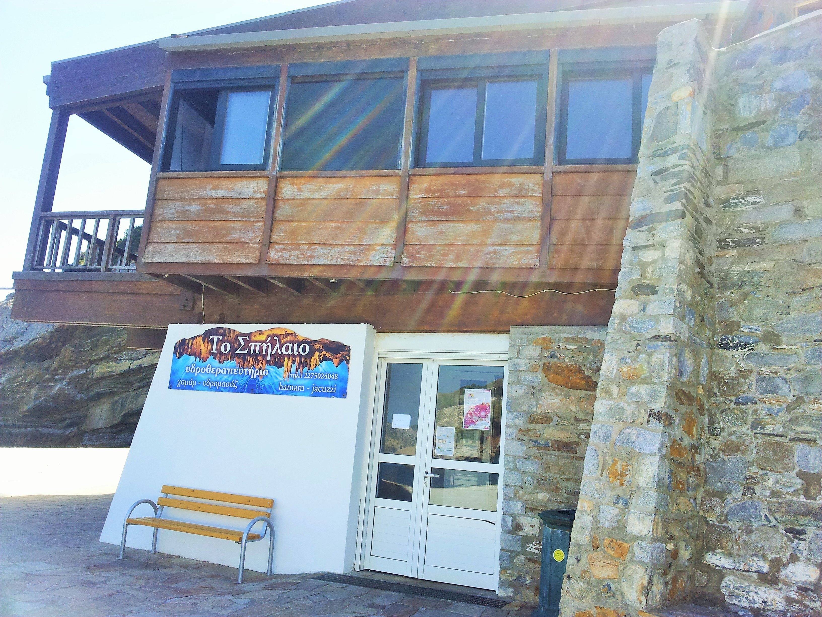 A building with a wooden balcony, a bench, and a signboard.