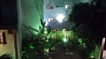 A multi-story building with a courtyard. The building has multiple windows and a sign that reads "KINGDOM". There are chairs and tables arranged in the courtyard.
