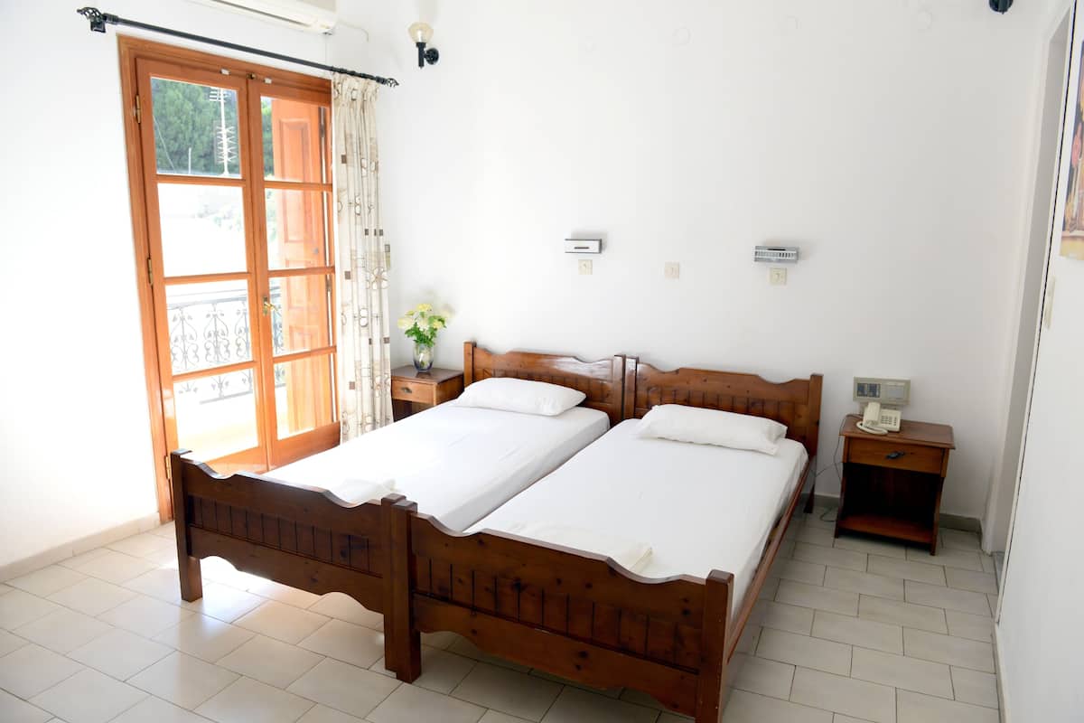A double bed with a wooden frame, a bedside table with a lamp, and a small bedside table with a telephone.