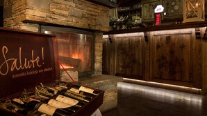 Una zona de bar acogedora con chimenea de piedra, armarios de madera y una vitrina para vinos.