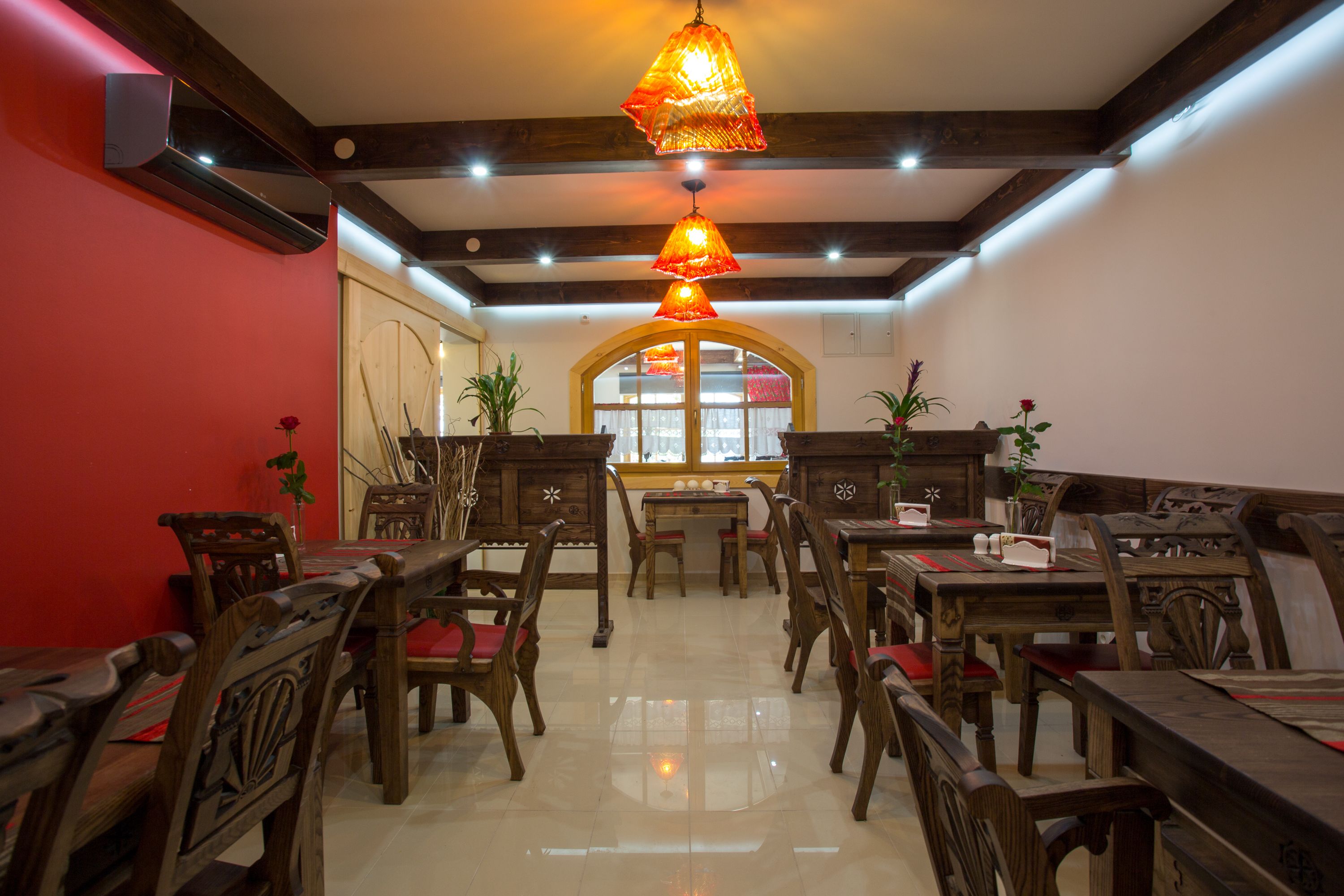 A dining area with wooden furniture, a central table, and hanging lamps.