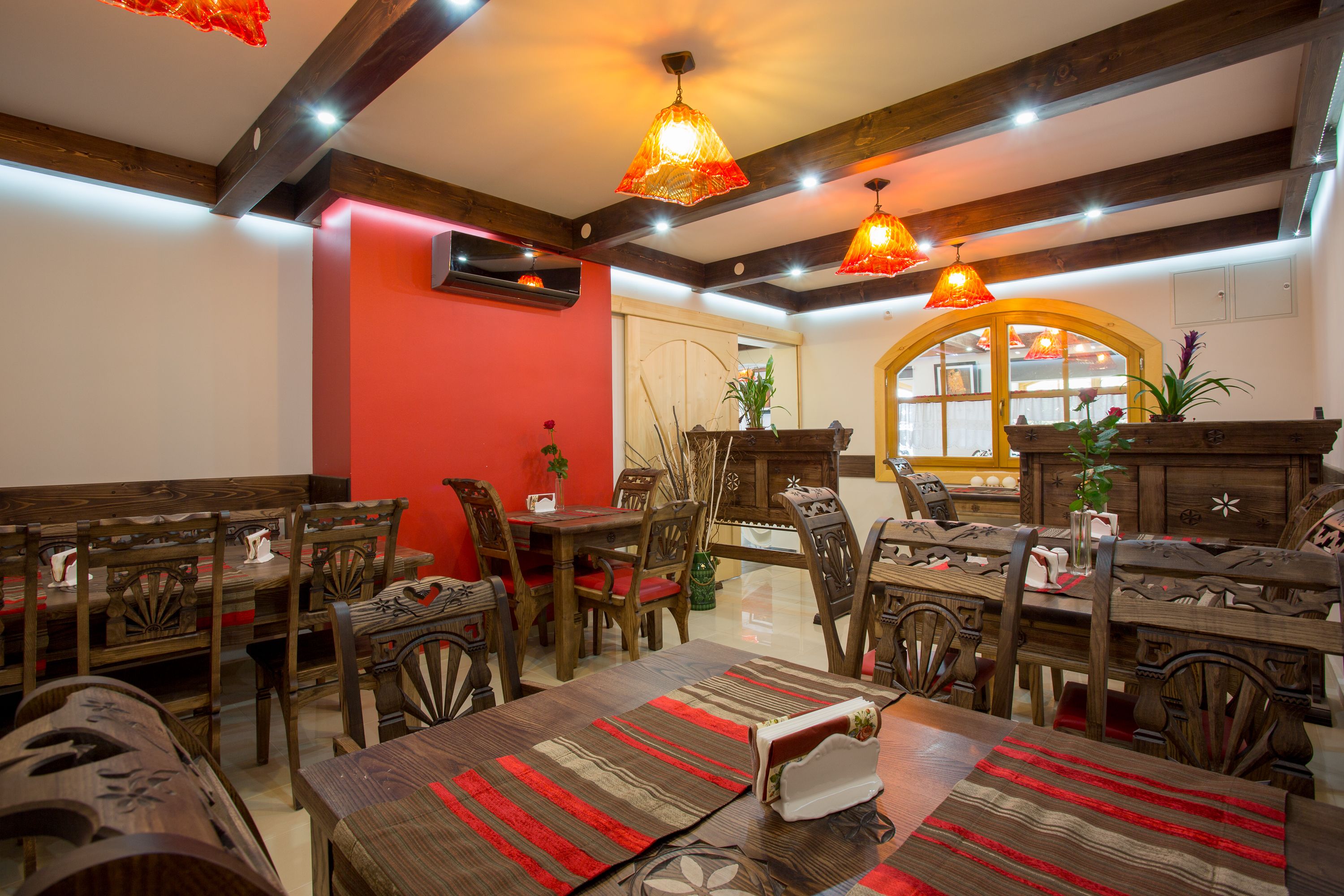 Un espace repas avec des meubles en bois, des murs rouges et des lampes suspendues.