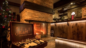 Una zona de bar con chimenea de piedra, un árbol de Navidad y una exhibición de vinos.