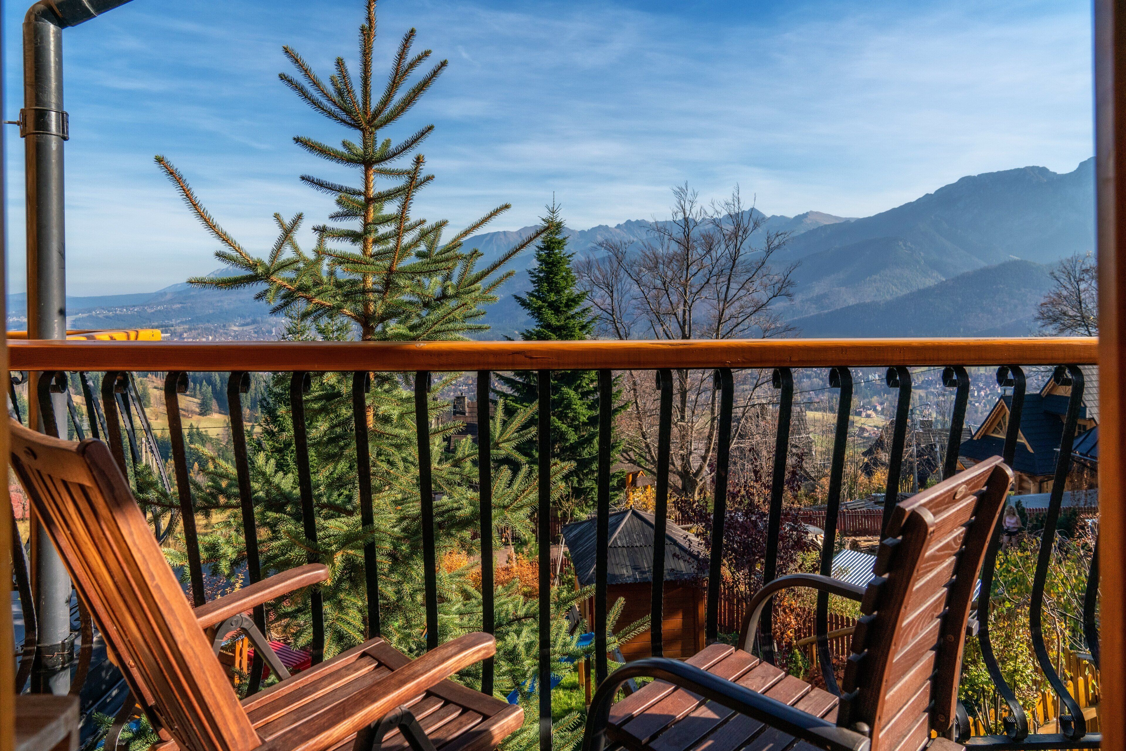 A balcony with wooden chairs and a view of mountains.
