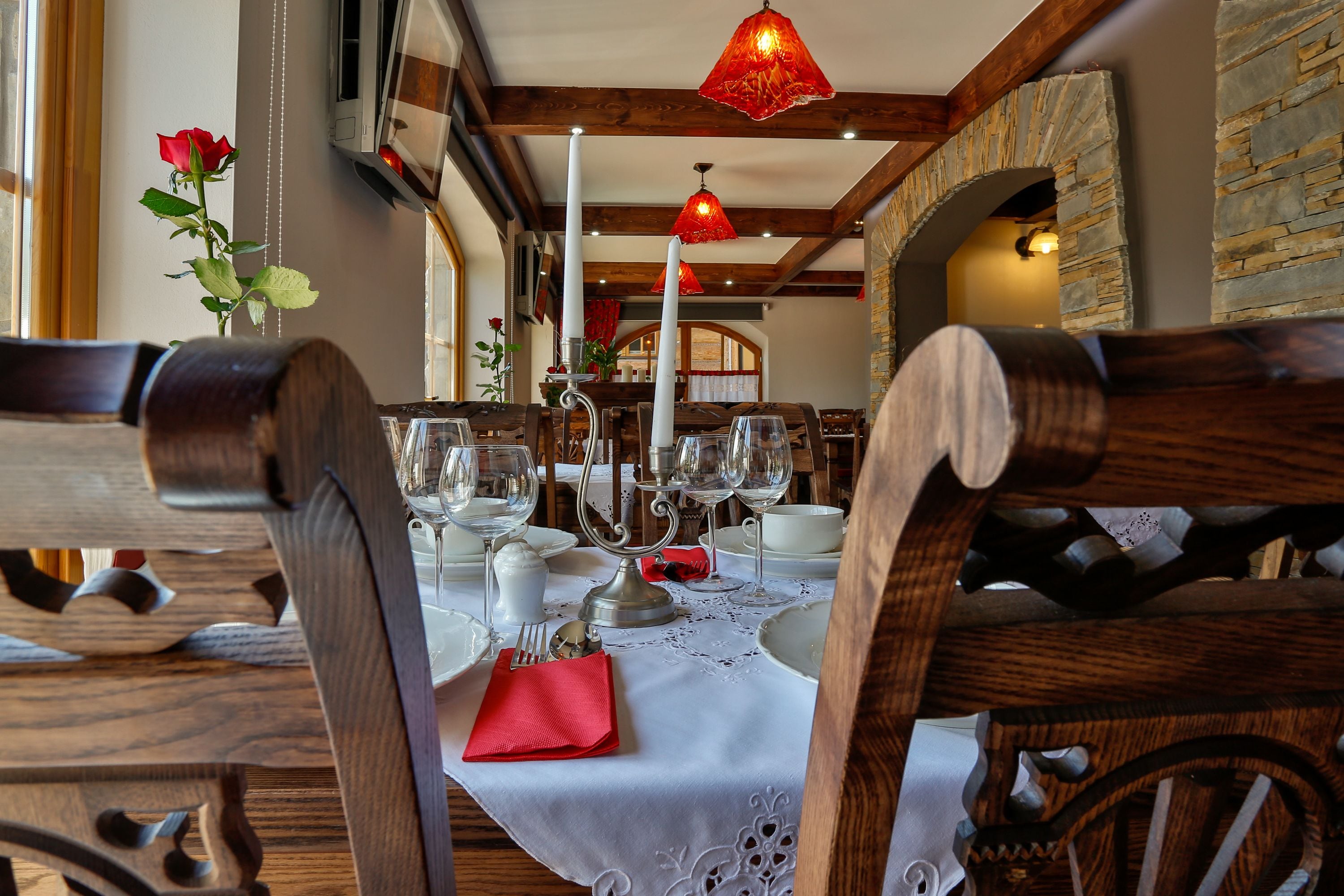 A dining area with wooden chairs, a white tablecloth, and red napkins.