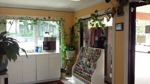 Una cocina con cafetera, un tablón de anuncios y una ventana con plantas.