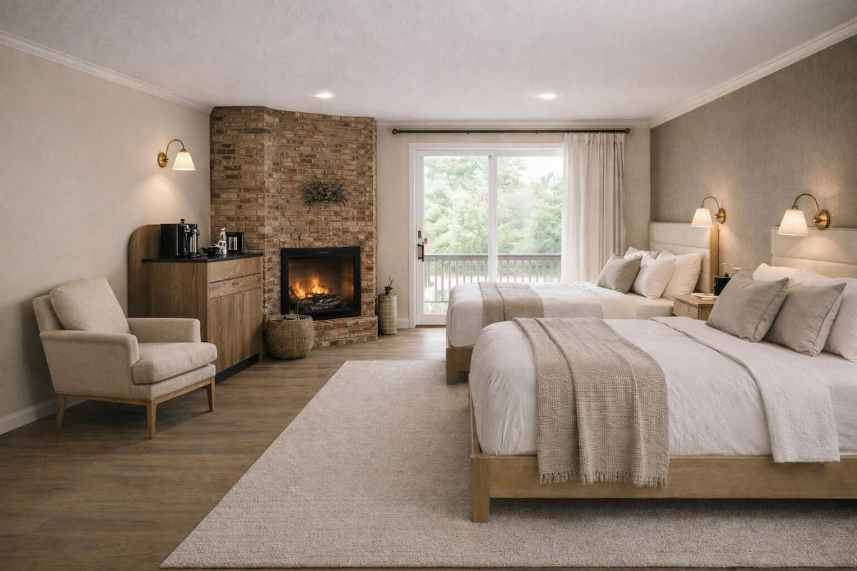 A bedroom with a fireplace, two beds, a chair, and a nightstand.
