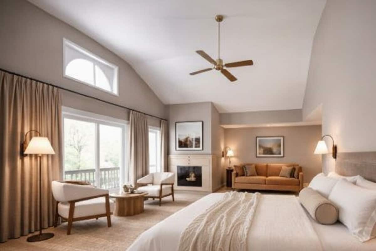 A spacious bedroom with a large bed, a ceiling fan, a fireplace, a sofa, and a view of the outdoors.