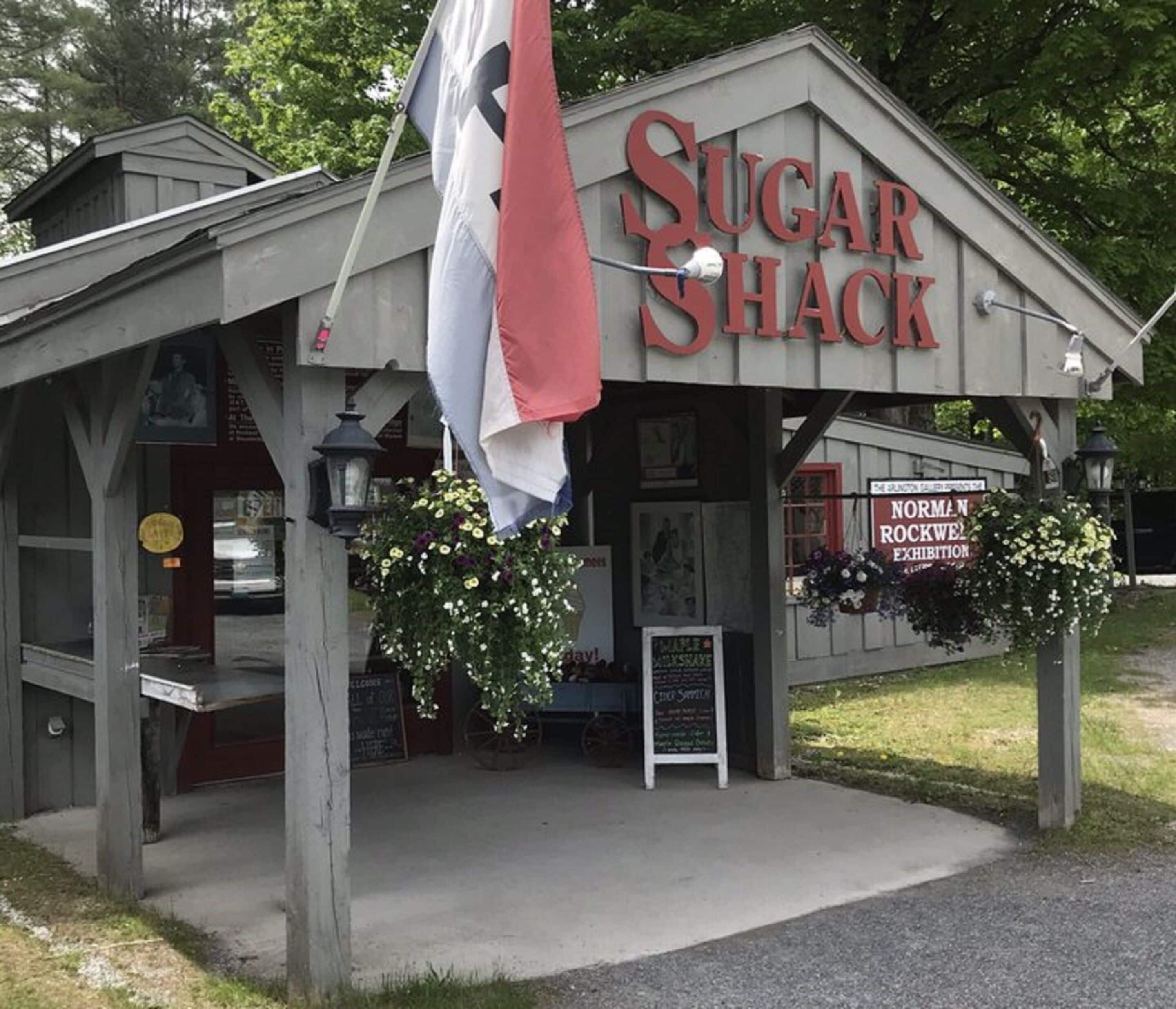 A rustic building labeled "Sugar Shack" with a sign for the Norman Rockwell exhibition.