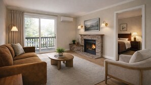 Un salon avec une cheminée, un canapé, une table basse et une vue sur l’extérieur, accessible par une porte-fenêtre coulissante.
