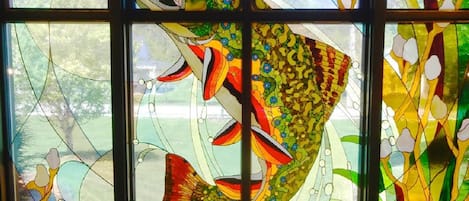 Une fenêtre en vitrail ornée d’un grand motif représentant un poisson.