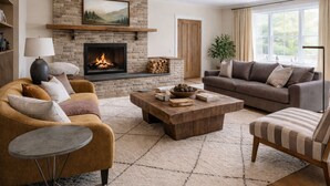 Un salon avec une cheminée, un canapé, une table basse et un fauteuil.
