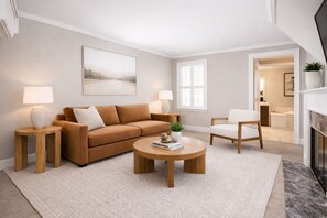 Un salon moderne comprenant un canapé, deux fauteuils, une table basse et une cheminée.