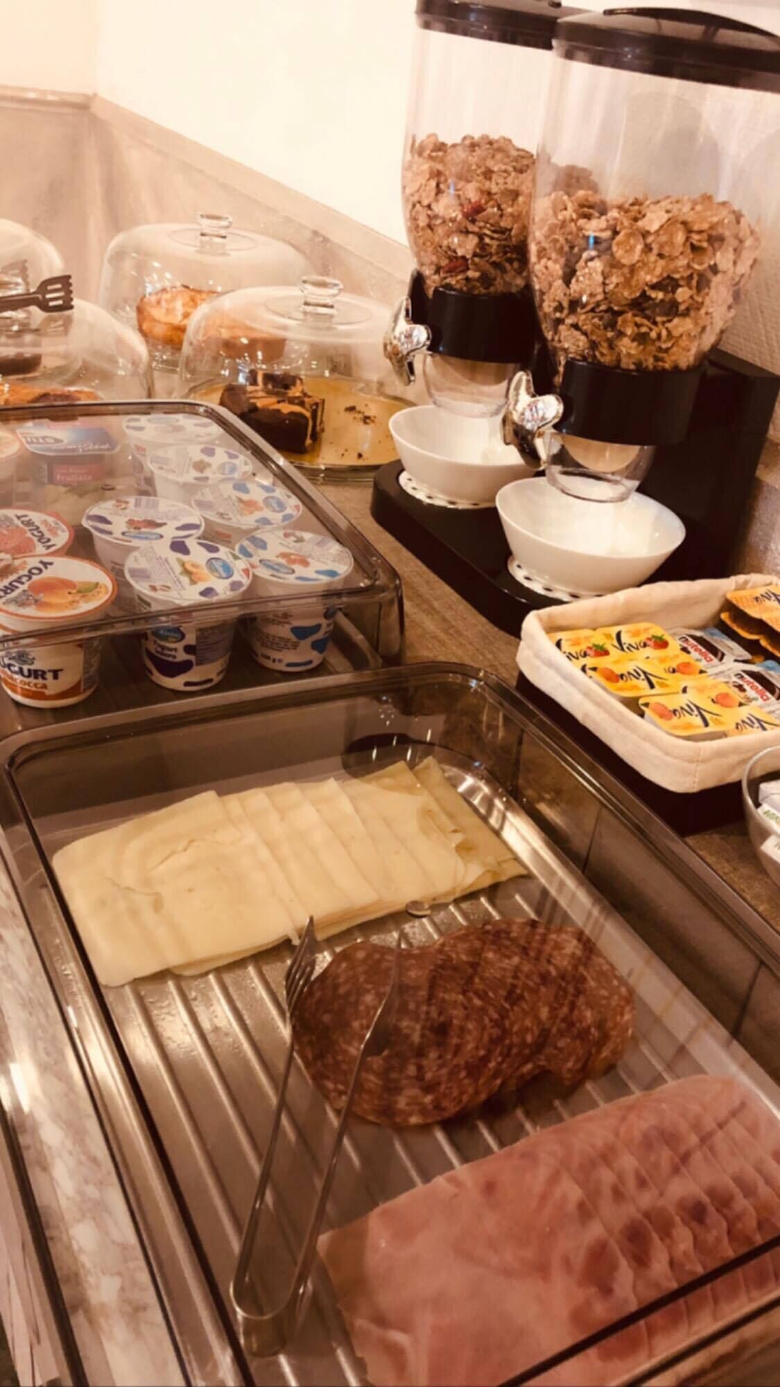 A buffet with various food items including yogurt, cereal, and meat.