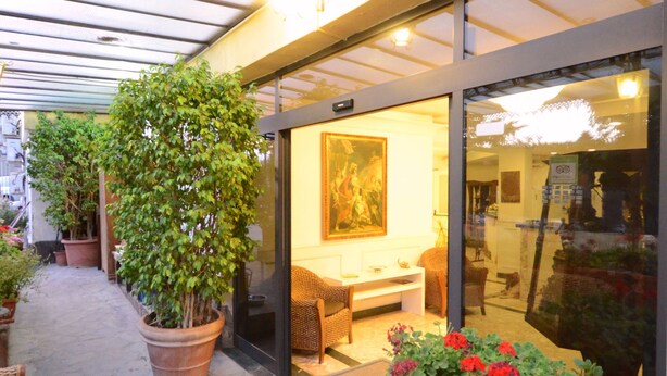 A covered outdoor area with potted plants and a seating area. - Hotel Clinton (Casoria)