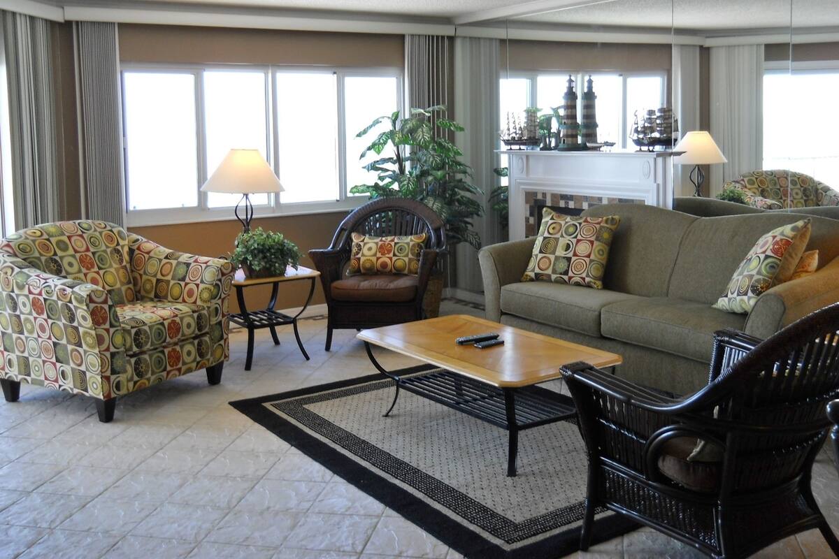 A living room with a sofa, armchairs, a coffee table, and a fireplace.