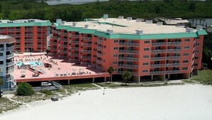Un hotel de varios pisos con piscina en la azotea y servicios junto a la playa.