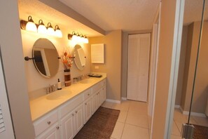 A bathroom with two sinks, a large mirror, and wall-mounted lights. - Beach Cottages (Indian Shores)
