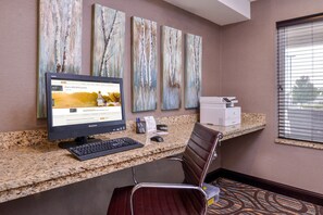 A hotel reception desk with a desktop computer, a chair, and artwork on the wall. - Holiday Inn Express & Suites Emporia Northwest by IHG (Emporia)