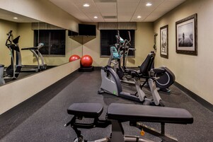 A gym with exercise equipment, a bench, and a mirror.