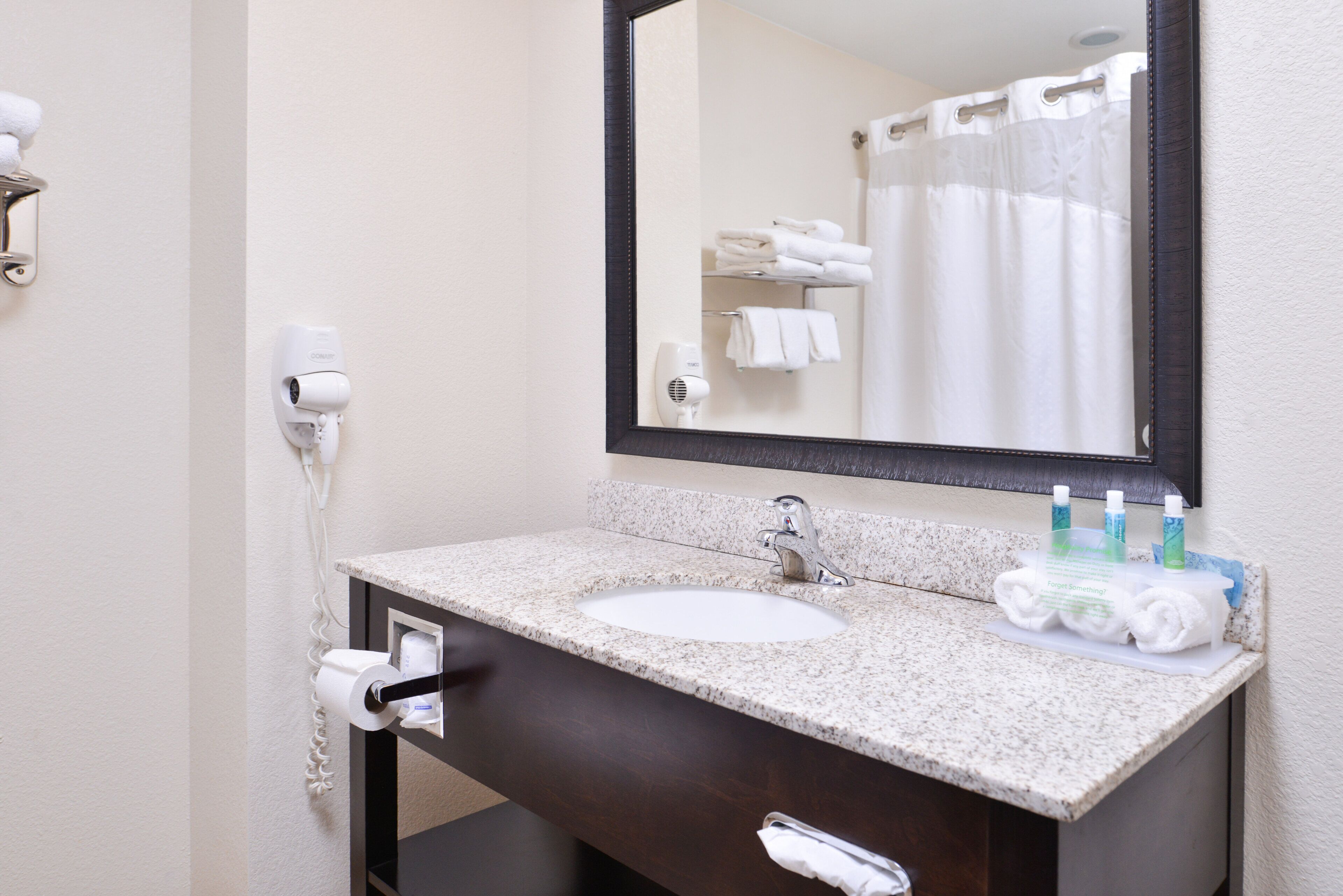 Un baño con lavabo, espejo, toallero y secador de pelo.