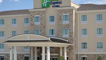 Ein Holiday Inn Express & Suites Gebäude mit einer steinernen Fassade, zahlreichen Fenstern und einem überdachten Eingang.