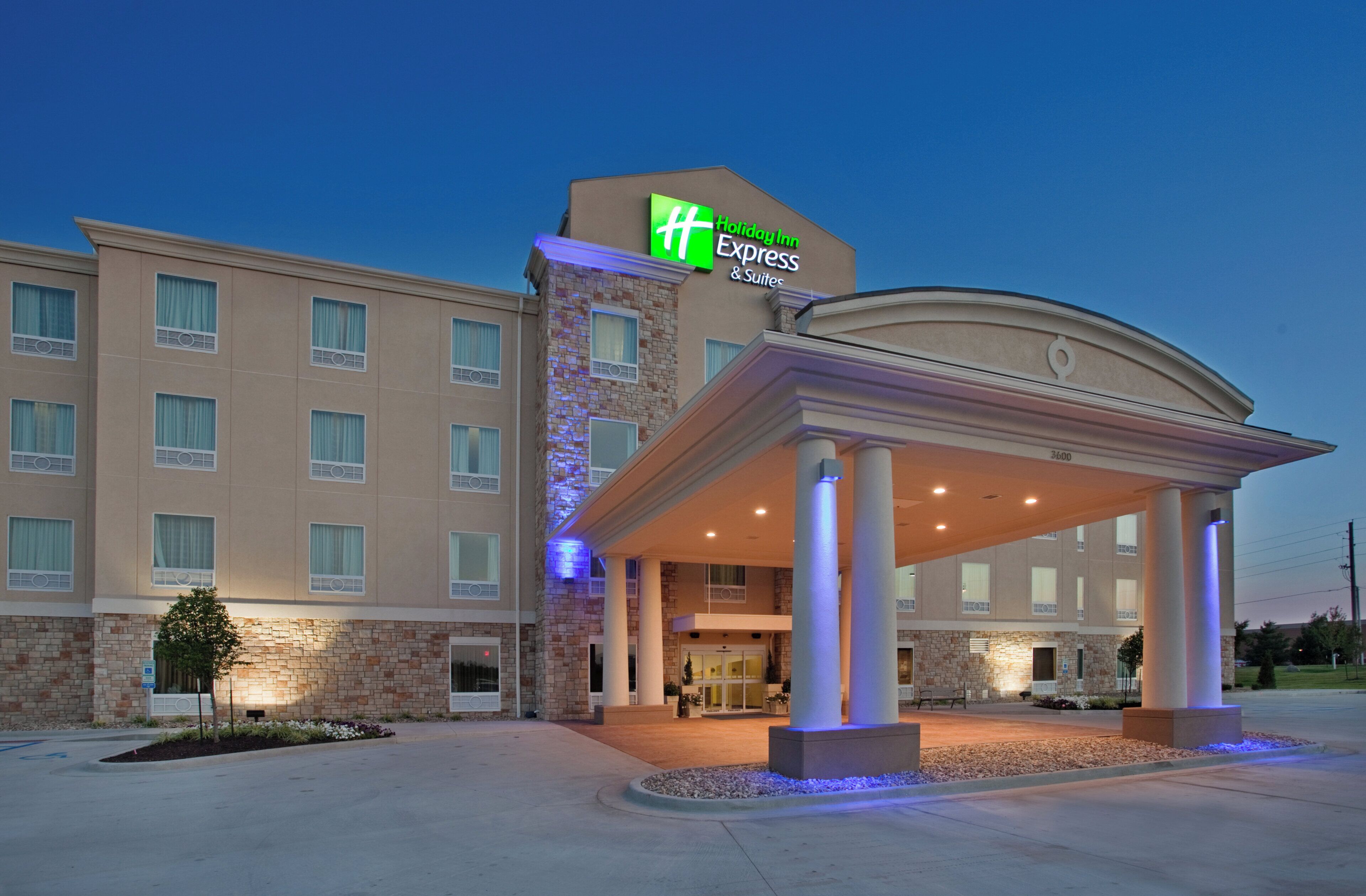 Un hôtel Holiday Inn Express & Suites doté d’une entrée couverte et d’une façade en pierre.