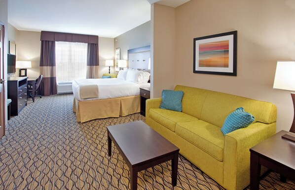 A hotel room with a bed, a sofa, a desk, and a chair.
