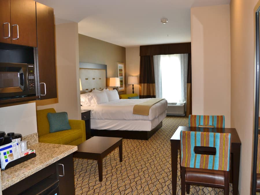 A hotel room with a bed, a sofa, a small table, a microwave, and a TV.