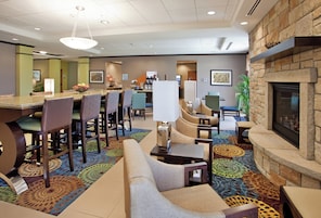 Un hall de hotel con zona de comedor, arreglos de asientos, una chimenea y una recepción.