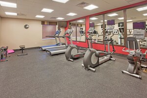 Un gimnasio con cintas de correr, elípticas y equipo de levantamiento de pesas.