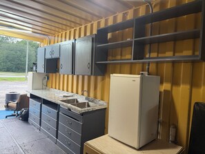 A compact kitchen with a sink, cabinets, and a refrigerator. - Western Motel (Jesup)