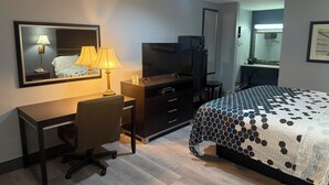 A hotel room with a bed, desk, chair, television, and a mirror. - Western Motel (Jesup)